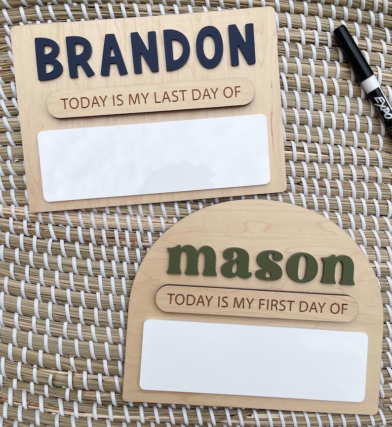 May include: Two wooden signs with white dry-erase panels. The rectangular sign features the dark blue name BRANDON and the text TODAY IS MY LAST DAY OF. The arched sign features the olive green name mason and the text TODAY IS MY FIRST DAY OF.