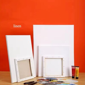 May include: A set of four white canvas boards, with the word "linen" printed on the top left corner of the image. The boards are different sizes and are stacked on top of each other. There are two tubes of paint in the bottom right corner of the image.