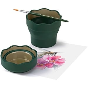 Puede incluir: Dos recipientes de agua plegables verdes con un pincel apoyado en la parte superior de uno. Los recipientes están diseñados para contener agua para pintar.