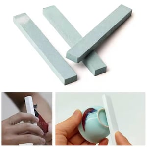 May include: Three light blue rectangular ceramic sharpening stones. The stones are used for sharpening knives, tools, and other objects. The stones are shown on a white background.