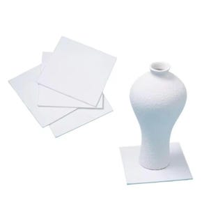 May include: Four white ceramic tiles stacked on top of each other. A white ceramic vase with a textured surface sits on a white ceramic tile.