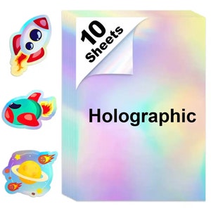 May include: A stack of 10 holographic sheets with a colorful, iridescent finish. The text "Holographic" is displayed in black. Three space-themed stickers of a rocket, a spaceship, and a planet are also visible.