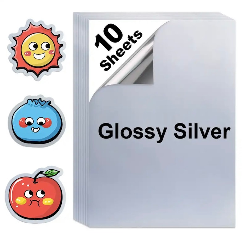 May include: A stack of 10 glossy silver sheets with the text "Glossy Silver". Three cartoon stickers of a sun, a blueberry, and an apple are on the left side of the image. The sun is yellow and red, the blueberry is blue, and the apple is red.