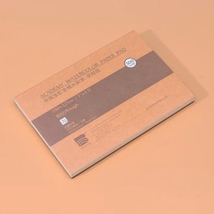 May include: A brown watercolor paper pad with the text "ACADEMY WATERCOLOR PAPER PAD" and "中国宝虹全棉水彩本/学院级" in Chinese. The pad is 180 x 125 mm or 7 x 4.9 inches and has a rough texture. It is made of 100% cotton and is acid free.