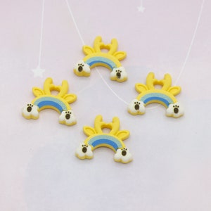 Puede incluir: Cuatro adornos amarillos y azules en forma de arcoíris con detalles de huellas de patas. Los adornos tienen un arco amarillo con un arcoíris azul y huellas de patas blancas. Ideales para manualidades.