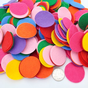 Può includere: Una collezione di cerchi di feltro colorati in varie dimensioni e tonalità, tra cui rosso, rosa, arancione, giallo, verde, blu e viola. Un quarto di dollaro americano è incluso come riferimento delle dimensioni. Questi materiali per l'artigianato sono ideali per progetti fai-da-te.