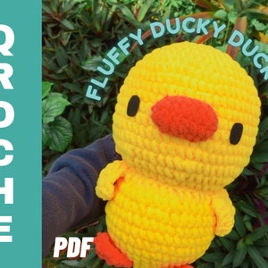 May include: A crocheted yellow duck plush toy with black eyes and a red beak. The toy is labeled "Fluffy Ducky Duck" in a white font.