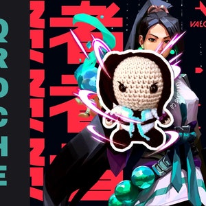 May include: A crocheted amigurumi figure of a character from the video game Valorant. The figure is wearing a black and white outfit with a blue and white scarf. The figure is standing in front of a character from the game, who is wearing a white and green outfit. The background is a black and red design with the word "VALORANT" in white.