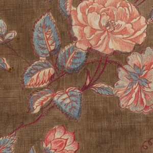 May include: A brown fabric with a floral pattern. The flowers are pink and white with blue and red leaves.