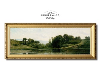 May include: A framed landscape painting depicting a serene lake scene with lush green trees and a cloudy sky. The painting is in a gold frame with ornate details.