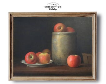 May include: A still life painting of red apples in a ceramic crock and on a white plate. The painting is framed in a light wood frame.