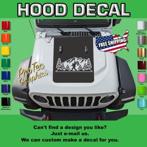 May include: A white Jeep with a black hood decal featuring a mountain scene with a figure holding a flag. The decal is surrounded by trees. The text "HOOD DECAL" is at the top. Color swatches are on the left and right.
