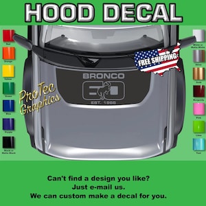 May include: A dark gray hood decal for a vehicle featuring the text BRONCO 60 EST. 1966 with a bucking horse silhouette. The decal is displayed on a vehicle hood with a color chart on both sides showing red, orange, yellow, green, blue, purple, black, white, silver, gold, burgundy, pink, lime, and teal options.