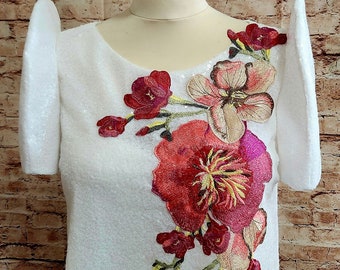 May include: White top with short sleeves and a floral embroidery design. The embroidery features pink, red, and yellow flowers.