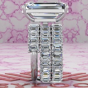 May include: A silver ring with three bands of emerald-cut diamonds. The top band features a larger emerald-cut diamond.
