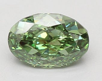 May include: An oval-cut gemstone in a vivid green colour. The gem's surface is covered in numerous facets, which catch and reflect light, producing a sparkling appearance. The shape is elongated with a rounded form.