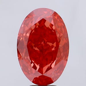 May include: A vibrant red oval-shaped gemstone with a faceted cut. The gemstone is set on a black stand.