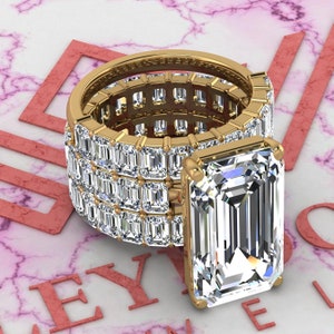 May include: A gold ring with a large emerald-cut diamond center stone and a band of smaller diamonds set in a pave setting.