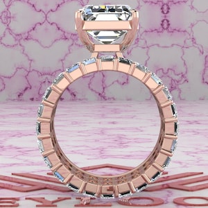 May include: A rose gold engagement ring with a large, square-cut diamond center stone and a band of smaller diamonds set in a pave setting.