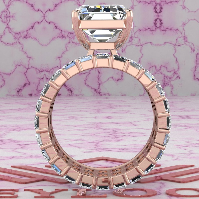 May include: A rose gold engagement ring with a large, square-cut diamond center stone and a band of smaller diamonds set in a pave setting.