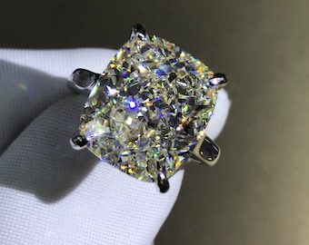 May include: A large, cushion-cut diamond engagement ring set in a silver band. The diamond is clear and sparkling.