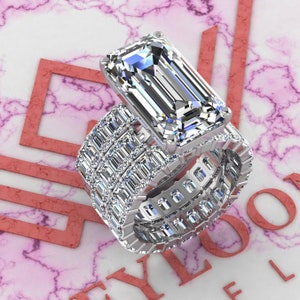 May include: A silver ring set with a large, clear emerald-cut diamond. The ring is surrounded by a band of smaller diamonds.
