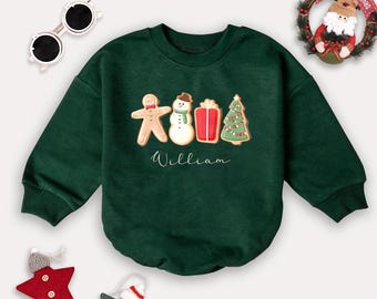 May include: A green Christmas sweater with gingerbread man, snowman, gift, and Christmas tree designs. The sweater has the name "William" printed on it.