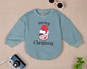 May include: A light blue sweatshirt with a cartoon cow wearing a Santa hat. The text "mooey christmas" is printed on the sweatshirt.