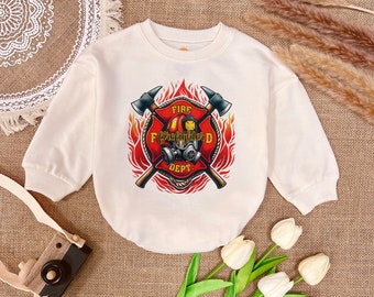 May include: A cream coloured long-sleeved sweatshirt with a graphic of a firefighter helmet, crossed axes, and the words "Fire Dept." and "Firefighter" in a red circle with flames.