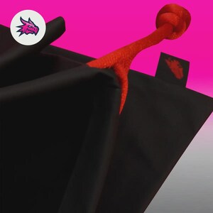 May include: Black bag with a red cord handle and a red logo tag. The bag is set against a bright pink background. A white circle with a pink dragon logo is in the upper left corner.