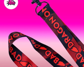 May include: Black and red lanyard with the text "Bad Dragon" repeated on both sides. The lanyard has a black metal clip.