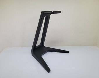 May include: A black metal stand with a triangular base and a single vertical support. The stand is designed to hold headphones.