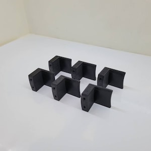 May include: Six black plastic corner brackets, each with four holes for mounting.