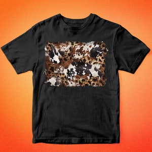 May include: Black t-shirt featuring a rectangular cowhide pattern in shades of brown, white, and black. The shirt has short sleeves and a crew neck. The text "BARKALOO DESIGN" is printed in white at the top and bottom of the image.