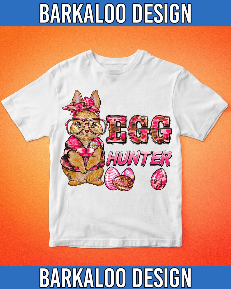 May include: White t-shirt featuring a cartoon bunny wearing glasses, a pink bandana, and a pink camo vest. The text "EGG HUNTER" is printed in pink and brown camo lettering, with three decorated Easter eggs below.