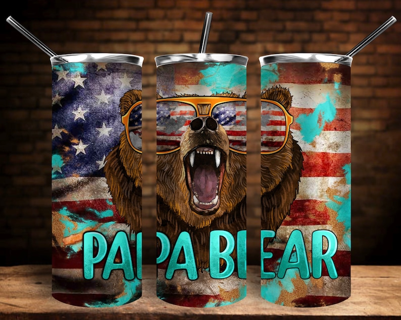 K&ouml;nnte beinhalten: Drei Edelstahlbecher mit patriotischem Thema. Jeder Becher zeigt einen braunen B&auml;ren mit Sonnenbrille und einem rot-wei&szlig;-blauen amerikanischen Flaggenmuster. Der Text "Papa Bear" ist in T&uuml;rkis auf der Vorderseite jedes Bechers aufgedruckt.