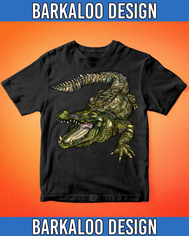 May include: Black t-shirt with a green and brown alligator graphic. The alligator is facing the viewer with its mouth open and teeth showing. The t-shirt has a crew neck and short sleeves.