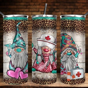 May include: Three stainless steel tumblers with a leopard print design and a white wood background. Each tumbler features a different gnome dressed as a medical professional. One gnome is a doctor, one is a nurse, and one is a first responder.