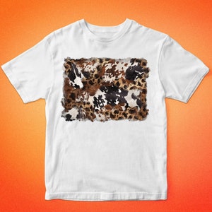 May include: White t-shirt featuring a cowhide pattern in shades of brown, black, and white. The shirt has short sleeves and a crew neck. The text "BARKALOO DESIGN" is printed above and below the shirt.