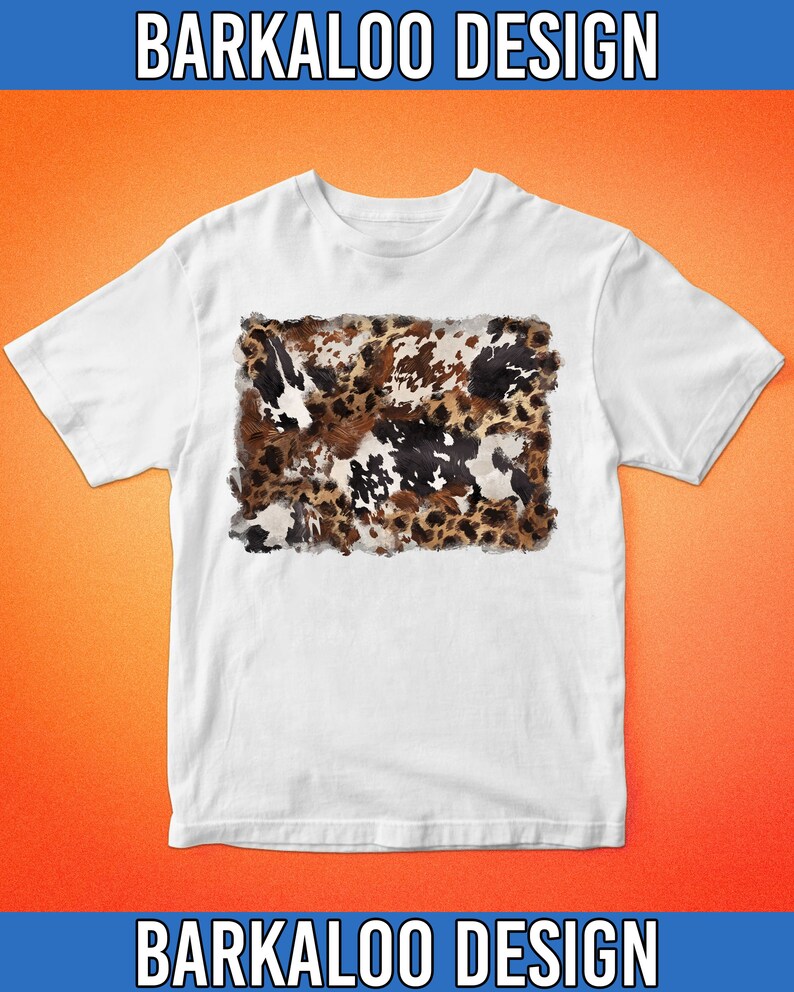 May include: White t-shirt featuring a cowhide pattern in shades of brown, black, and white. The shirt has short sleeves and a crew neck. The text "BARKALOO DESIGN" is printed above and below the shirt.