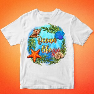 Op de afbeelding: Wit T-shirt met een blauw, groen en oranje ontwerp van zeeleven. Het ontwerp bevat een zeester, schelpen, zeewier en de tekst "Ocean life".