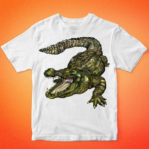 May include: White t-shirt with a green and brown alligator graphic. The alligator has its mouth open and is facing the right side of the image. The t-shirt has the text "BARKALO DESIGN" at the top and bottom of the image.