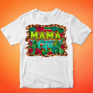 May include: White t-shirt with a colorful graphic design. The design features the words "MAMA Cita" in green and turquoise, surrounded by cacti, roses, and a leopard print border. The text "BARKALOO DESIGN" is at the top and bottom.