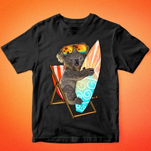 May include: Black t-shirt featuring a cartoon koala wearing sunglasses and holding a surfboard. The koala is sitting in a beach chair with a red, white, and blue striped design. The surfboard has a blue, green, and white design with swirls.