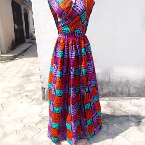 May include: A long, sleeveless dress with a wrap-style bodice and a flowing skirt. The dress is made of a colorful fabric with a geometric pattern in shades of orange, purple, turquoise, and black.