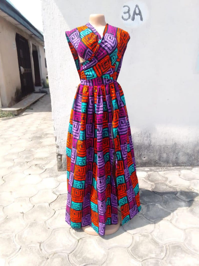 May include: A long, sleeveless dress with a wrap-style bodice and a flowing skirt. The dress is made of a colorful fabric with a geometric pattern in shades of orange, purple, turquoise, and black.