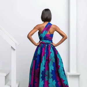 May include: A long, flowing dress with a one-shoulder design. The dress is made of a colorful fabric with a floral pattern in shades of blue, teal, pink, and purple.