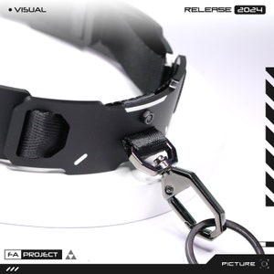 May include: Black collar with a metal clasp and key ring. The collar has a black nylon strap and a metal plate with a geometric design. The text "VISUAL" and "RELEASE 2024" are visible.