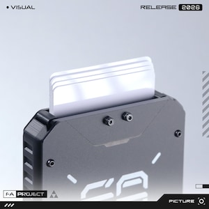 May include: A matte black metal card holder with a stack of white cards inserted at the top. The front features two small exposed screws and white graphic text. The top corners of the holder are angled, and the side has a textured grip pattern.