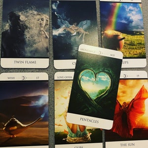 Puede incluir: Tirada de cartas de tarot con diez cartas, incluyendo La Estrella, El Sol, La Llama Gemela, La Ascensión, La Unión, La Felicidad, La Oferta de Amor, Las Copas, Los Pentaculos y La Abundancia. Las cartas están dispuestas en una cuadrícula sobre una superficie gris.